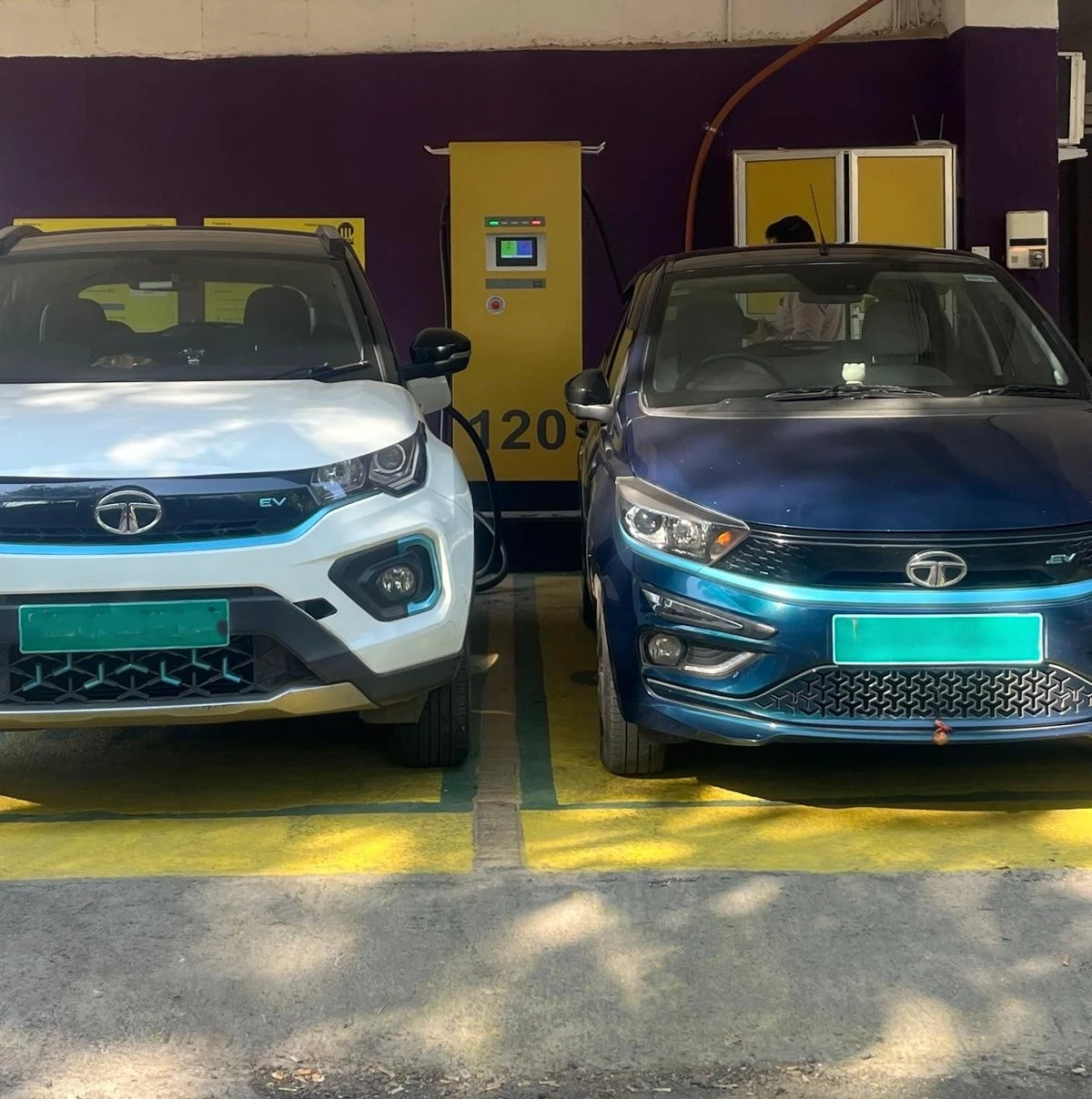 Two electric cars charging at dual EV charging station in parking area with fast charger installed